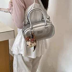 Détail de sac bandoulière Boston métallisé argenté avec adorable pendentif d'ours.