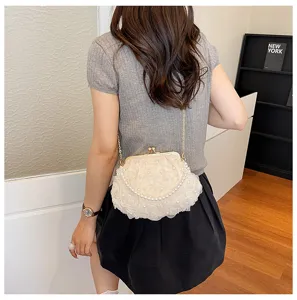 Detail view of a white floral rose kiss-lock pearl chain crossbody bag worn on model.