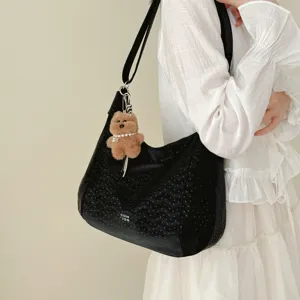 Detail shot of black hobo shoulder bag with perforated chevron pattern and cute bear keychain.