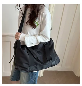 Detailed view of the black travel duffel bag worn on shoulder, showing casual daily style use.