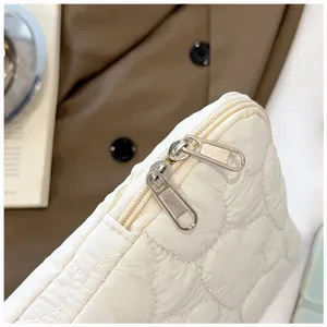 Detalle de bolsa de almacenamiento acolchada blanca, textura suave con doble cremallera metálica.