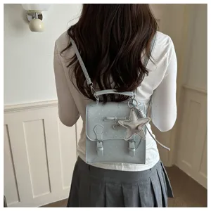 Detail view of a light blue polka dot mini backpack for women with a cute star pendant.