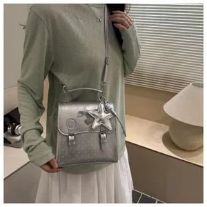 Silver polka dot mini backpack detail featuring metallic handle and cute star pendant charm.