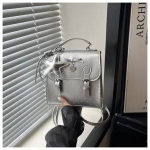 Detail view of the silver mini backpack with cute star pendant and bow design close-up.