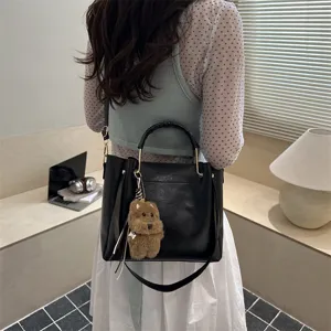 Vintage black bucket bag for women, stylish crossbody shoulder handbag with cute bear charm.
