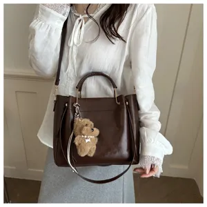 Retro textured women bucket bag detail view, casual fashion crossbody bag with cute dog charm.