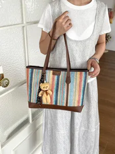 Colorful woven straw tote bag with brown leather trim and cute teddy bear pendant charm.