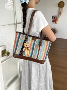 Woven tote bag detail showcasing colorful pattern, brown leather trim, and cute teddy bear pendant.