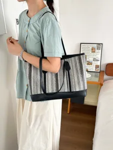 Detailed view of the woven tote bag showcasing textured black and white patterns and leather trim.