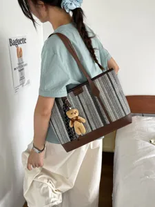 Stylish woven tote bag with brown leather trim and cute bear pendant for women daily commute.