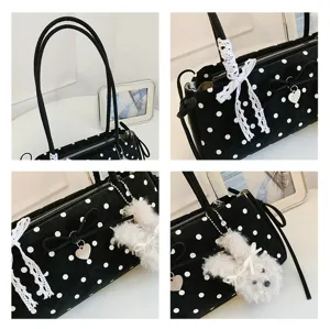 Close-up detail shot of black polka dot shoulder bag with lace bow and cute plush pendant.