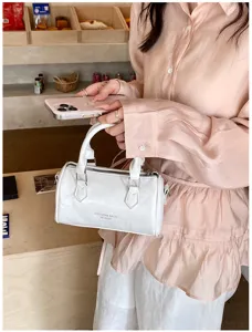 Trendy white barrel bag for women, stylish PU leather top handle pillow purse for daily wear.