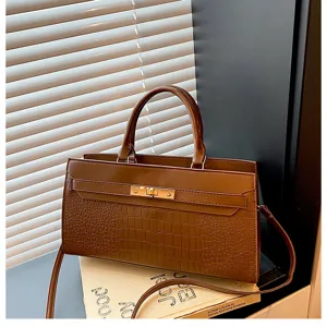Detailansicht der stilvollen braunen Kroko-Handtasche mit goldfarbenem Schloss und Gurt.