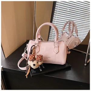 Pink barrel handbag detail featuring glossy PU leather, metal zipper, and cute bear pendant.