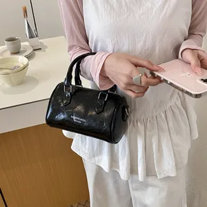 Black patent leather barrel handbag for women, stylish vintage shoulder pillow bag for daily use.