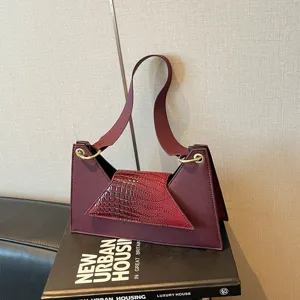 Detailed shot of the stylish burgundy trapezoid shoulder bag with crocodile texture flap.