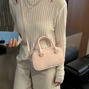 Detail view of the pink solid color handbag with embossed text, stylish everyday accessory.