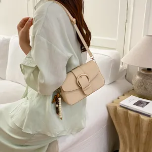 Chic minimalist shoulder bag for women, elegant beige design with round buckle and bead charm.