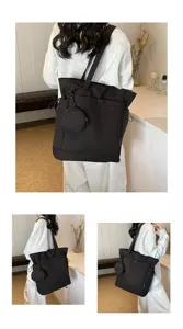 Detail view of a large black tote bag with coin purse, showing shoulder carry and style.