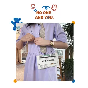 Gros plan detail du sac bandouliere enveloppe PU imprime papier journal avec chaine.