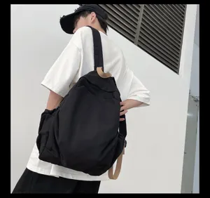 Detailaufnahme eines minimalistischen schwarzen Rucksacks mit Khakigurten an einer Wand.