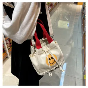 Leinwand Eimer Tasche Detail mit koreanischem Stil lachend Gesicht Druck und roten Griffen.