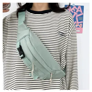 Detailaufnahme einer lässigen Brusttasche in Hellgrün mit verstellbarem Gurt und praktischer Schnalle.