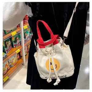 Stoff Eimer Tasche mit gelbem Smiley Gesicht, roten Henkeln und Schultergurt für den Alltag.