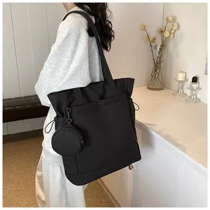 Detail view of the black tote bag with a small coin purse, side drawstrings and capacity.
