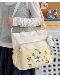 Detailansicht der niedlichen Canvas-Umhängetasche mit Cartoon-Bestickung und Plüsch-Anhänger.