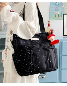 Vista detallada del bolso tote de lunares con lazos y colgante de manzana para uso diario y estudio.