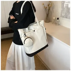 Detailed shot of large capacity white tote bag with small coin purse, carried on shoulder.