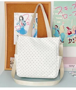 Vista detallada de un bolso tote blanco con lunares en un escritorio ordenado con papelería.