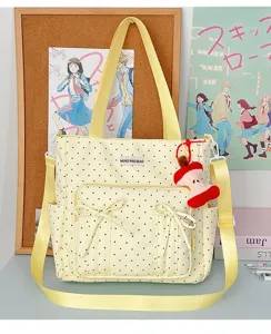 Vista detallada del bonito bolso tote de lunares amarillos con lazos y llavero de manzana.