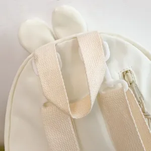 Vista dettagliata di un grazioso zaino studentesco in nylon bianco con orecchie di coniglio.
