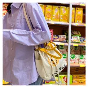 Leinwand Eimer Tasche für Frauen lässige Schultertasche mit süßem Smiley Druck und gelben Gurten.