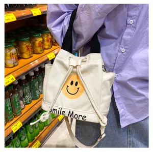 Detailansicht der Canvas-Tasche mit Smiley-Druck, schwarzen Trägern und Kordelzugverschluss.