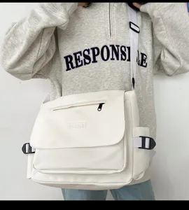 Details der weißen Canvas-Umhängetasche mit Vordertasche und verstellbarem Riemen.