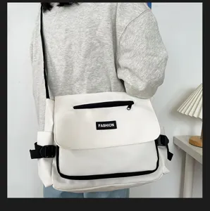 Detailaufnahme einer lässigen weißen Umhängetasche mit schwarzem Besatz und praktischer Fronttasche.