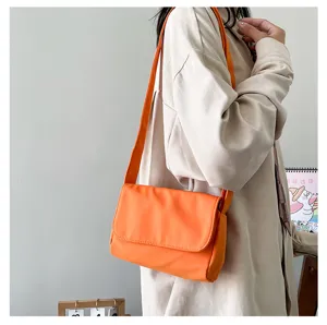 Minimalistische orangefarbene Umhängetasche Detail, einfarbige kleine quadratische Tasche Alltag.