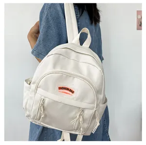 Kompakter, leichter, minimalistischer weißer Rucksack mit Vordertasche und Schultergurten.