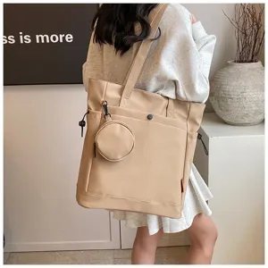 Close-up detail shot of the beige tote bag worn on shoulder, showing capacity and coin purse.