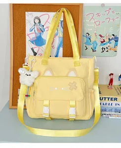 Detailansicht der gelben Katzenohr-Segeltuchtasche mit Stickerei und Plüschbär-Anhänger.