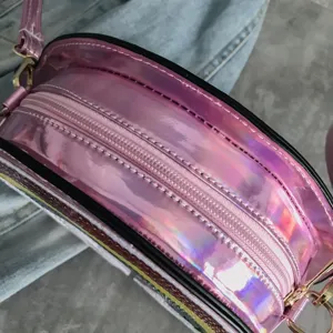 Bolso cruzado redondo holográfico rosa con cierre de cremallera y acabado brillante.