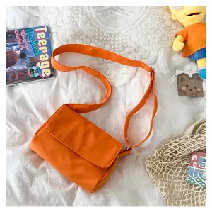 Detailansicht einer einfachen einfarbigen orangen Umhängetasche mit Klappe und verstellbarem Gurt.