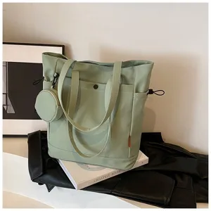 Closeup of a stylish sage green canvas tote bag featuring a matching coin purse and handles.