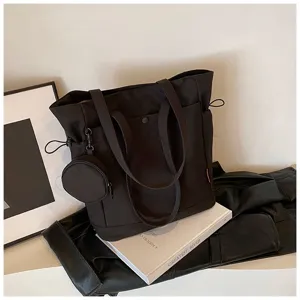 Detail view of a black canvas tote bag with side pockets, double handles and coin pouch.