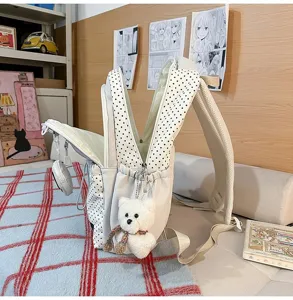 Detailed view of cute polka dot school backpack with adorable bear pendant and mesh straps.