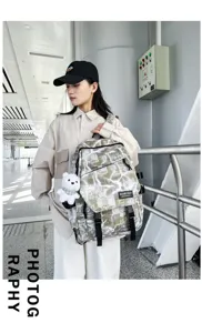 Stylish graffiti canvas backpack with adjustable straps and cute bear pendant for daily use.