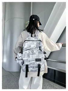 Detail view of trendy graffiti student backpack with newspaper print and bear pendant.